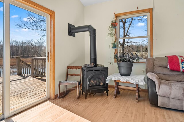 living area with baseboards, wood finished floors, and a wood stove