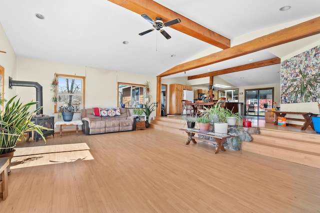 living room with lofted ceiling with beams, recessed lighting, wood finished floors, ceiling fan, and a wood stove