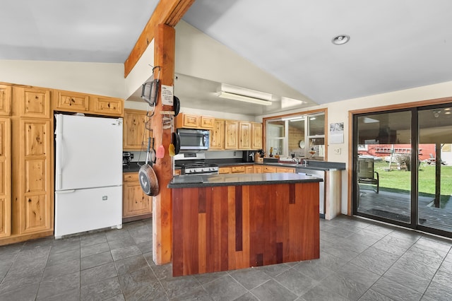kitchen with a center island, stainless steel appliances, vaulted ceiling, and dark countertops