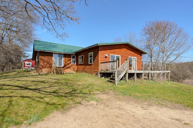 rear view of house featuring a wooden deck, entry steps, and a lawn