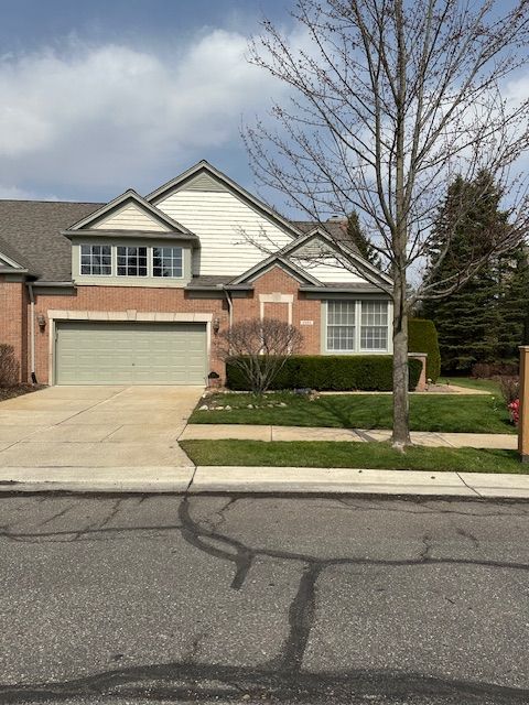 5081 Belmonte Dr, Rochester, MI 48306 - view of front facade featuring brick siding, an attached garage, driveway, and a front lawn