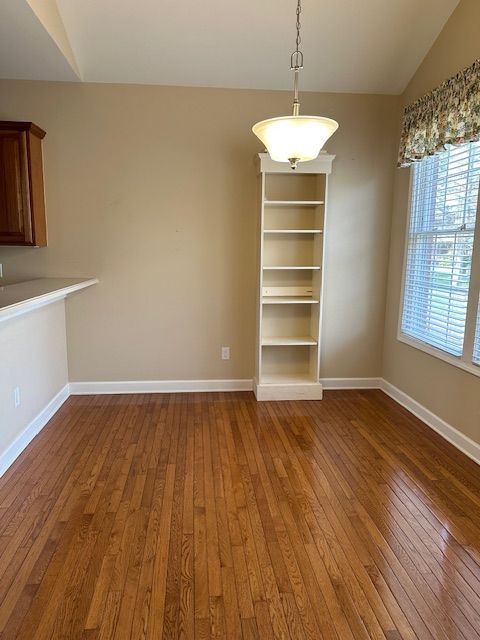 5081 Belmonte Dr, Rochester, MI 48306 - unfurnished dining area featuring vaulted ceiling, baseboards, and wood-type flooring