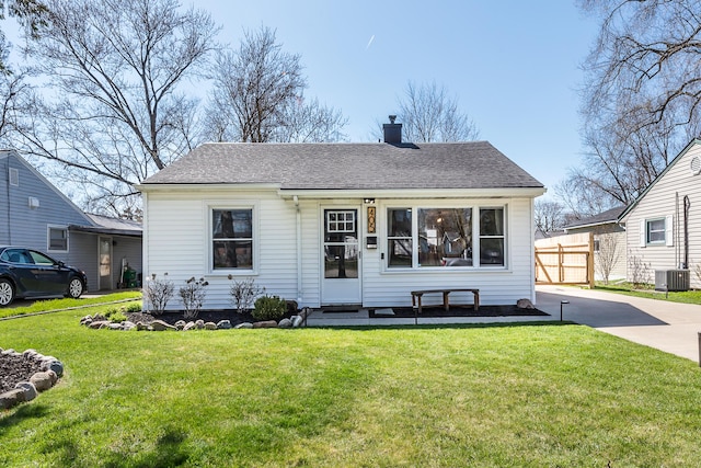 bungalow-style home with a chimney, a shingled roof, a front lawn, entry steps, and cooling unit