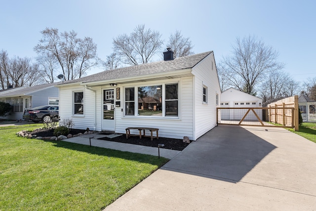 bungalow-style home with a chimney, an outdoor structure, roof with shingles, and a front lawn