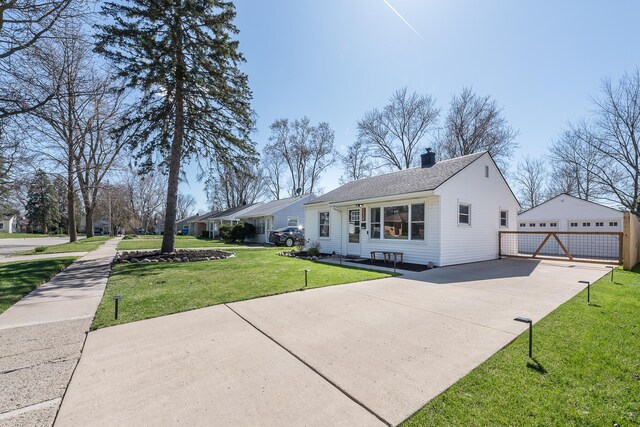 view of front of home featuring a chimney, a shingled roof, an outbuilding, a detached garage, and a front yard