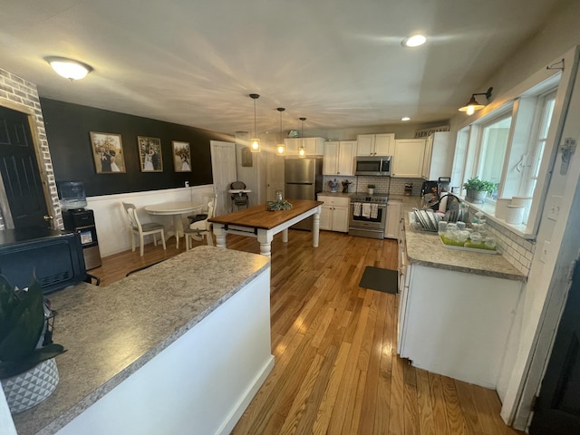7801 S Lucas Rd, Mcbain, MI 49657 - kitchen featuring white cabinets, a sink, light wood-style floors, decorative backsplash, and appliances with stainless steel finishes