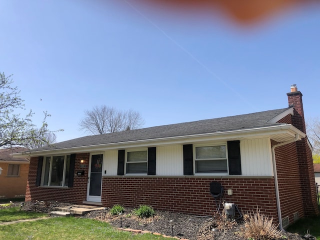 single story home with brick siding, a shingled roof, and a chimney