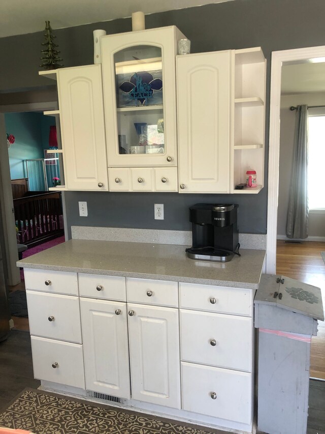kitchen with open shelves, glass insert cabinets, white cabinets, and dark wood-style flooring
