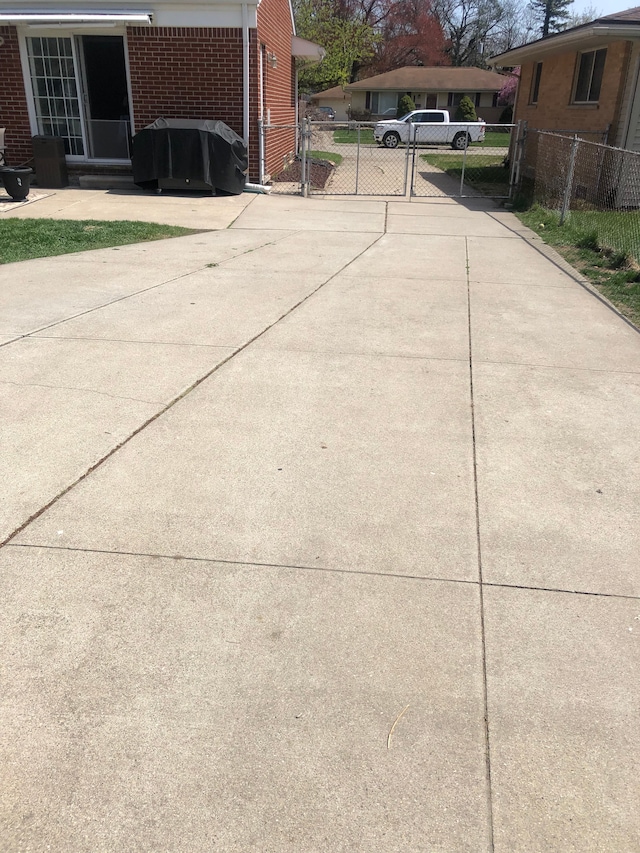 details featuring a gate, brick siding, concrete driveway, and fence