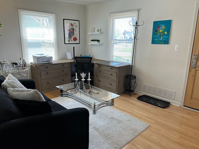 living room with light wood-type flooring, baseboards, and visible vents