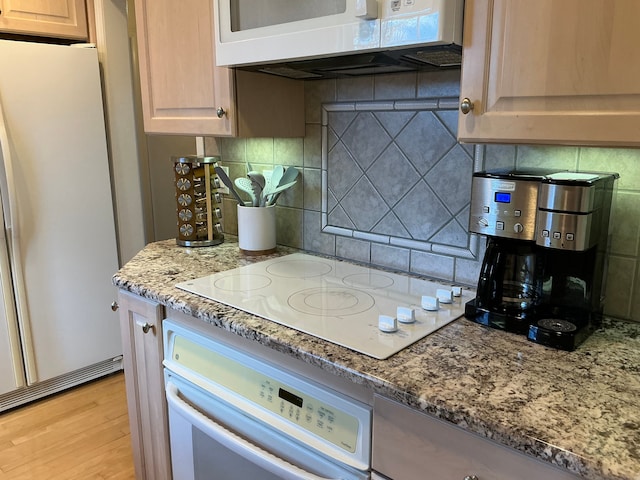 kitchen with decorative backsplash, white appliances, light wood-style floors, and light stone counters