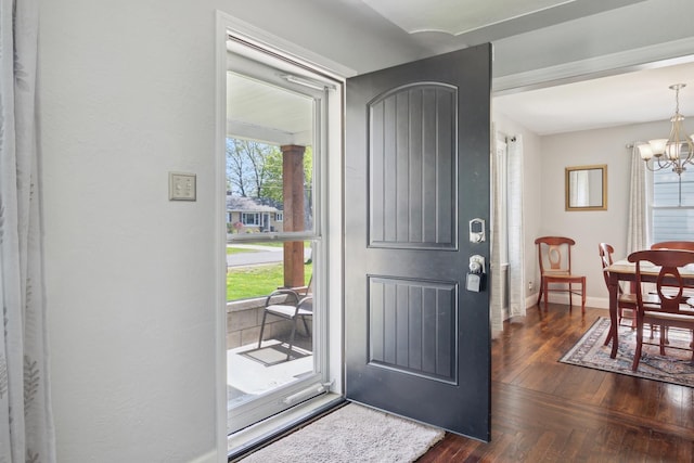 foyer featuring parquet floors, baseboards, a chandelier, and plenty of natural light