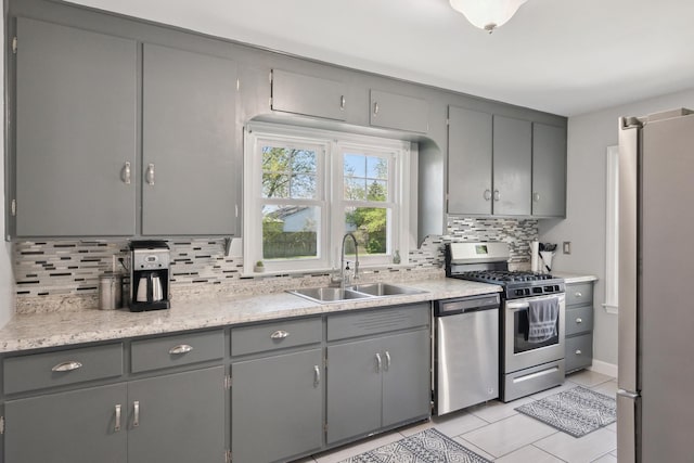 kitchen featuring a sink, gray cabinets, appliances with stainless steel finishes, and tasteful backsplash