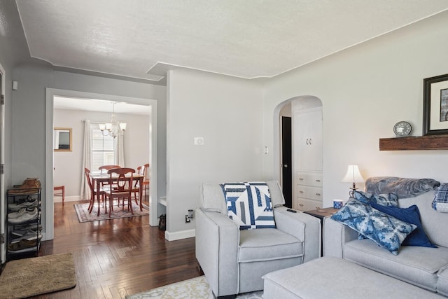 living area with baseboards, arched walkways, and a chandelier