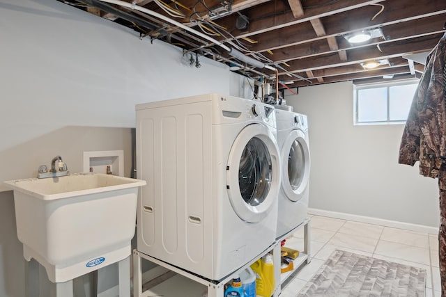 washroom featuring a sink, baseboards, laundry area, and independent washer and dryer