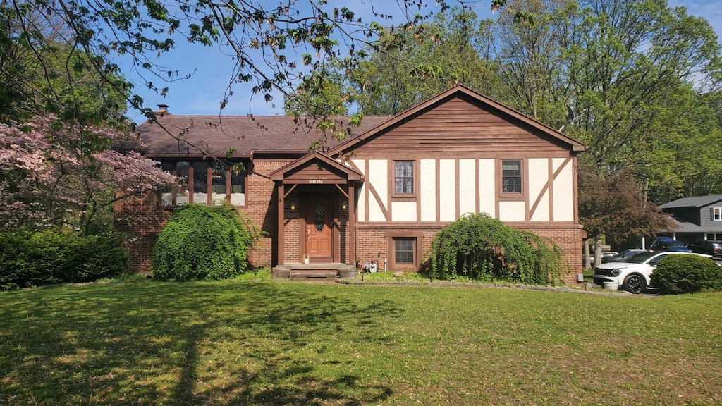 english style home featuring a front lawn and brick siding