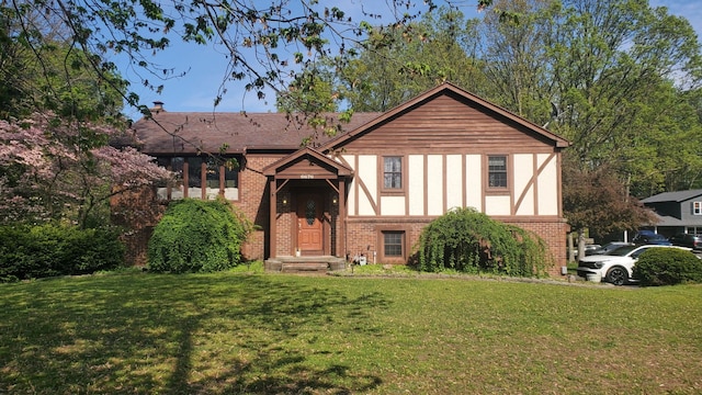 english style home featuring a front lawn and brick siding