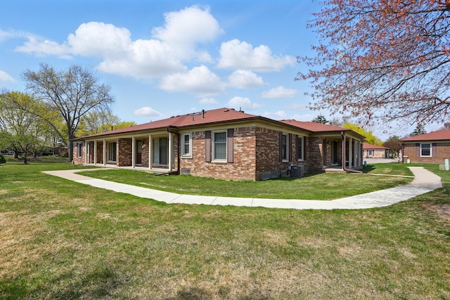 back of house with a lawn, brick siding, and central AC