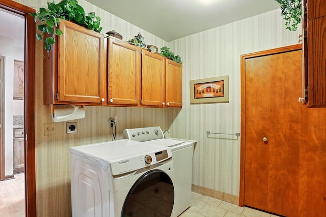 laundry area with wallpapered walls, cabinet space, light tile patterned floors, and washer / dryer
