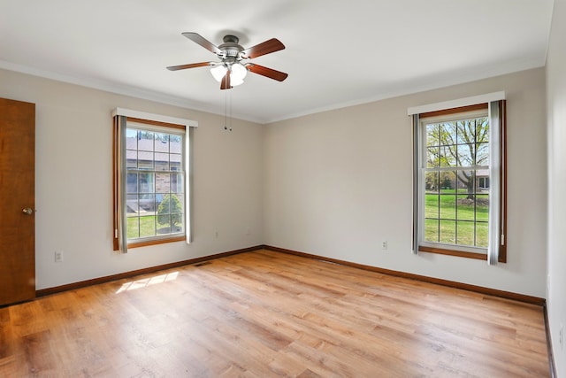 empty room with baseboards, a wealth of natural light, light wood-style floors, and crown molding