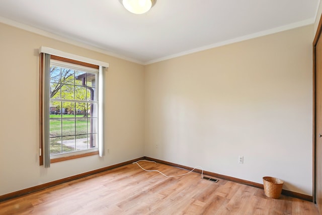 empty room with baseboards, light wood-style flooring, visible vents, and crown molding