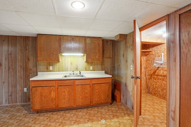 kitchen featuring wooden walls, light countertops, and a sink