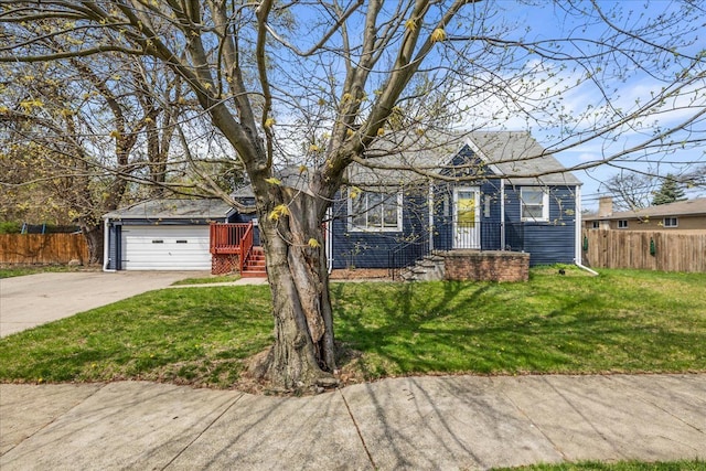 view of front facade with concrete driveway, a front yard, and fence