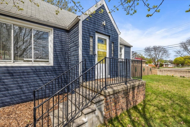 exterior space featuring a yard and a shingled roof