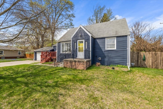 bungalow-style home featuring fence, a front yard, a shingled roof, and an outbuilding