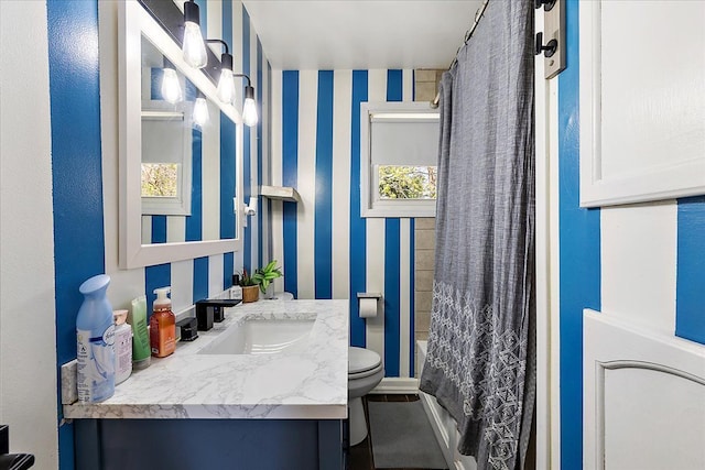 full bath featuring toilet, shower / tub combo with curtain, wallpapered walls, and vanity