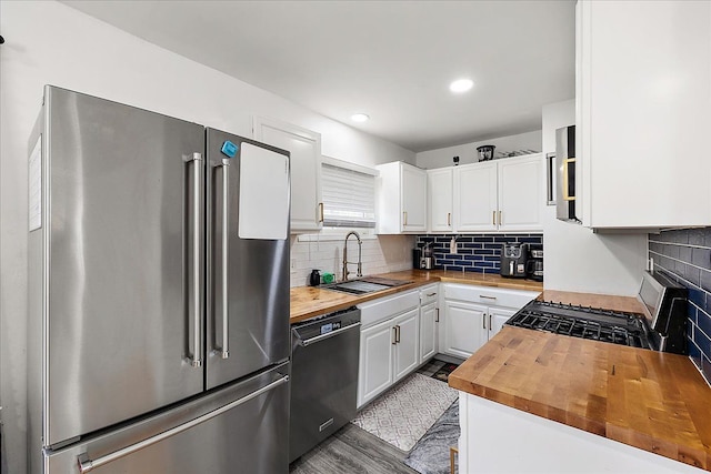 kitchen featuring wooden counters, a sink, white cabinets, and appliances with stainless steel finishes