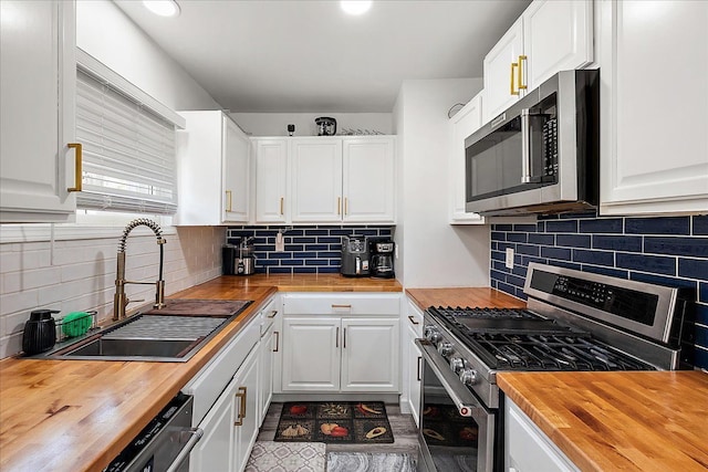 kitchen with white cabinetry, decorative backsplash, a sink, stainless steel appliances, and butcher block counters