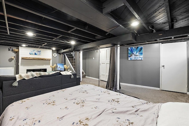carpeted bedroom featuring a fireplace and baseboards