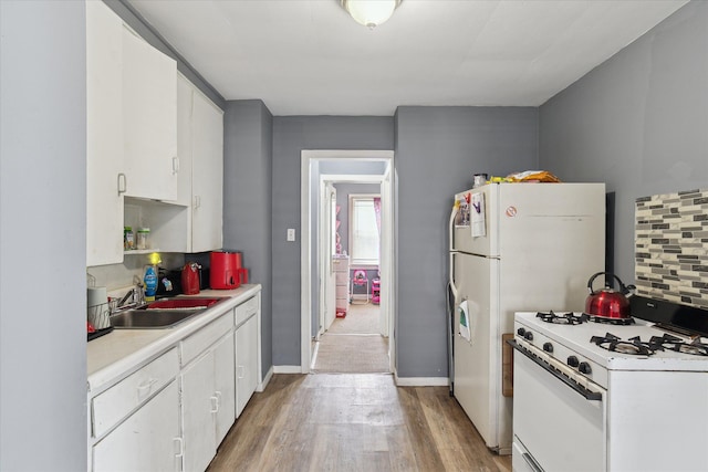 kitchen featuring white range with gas stovetop, a sink, light wood finished floors, light countertops, and white cabinets