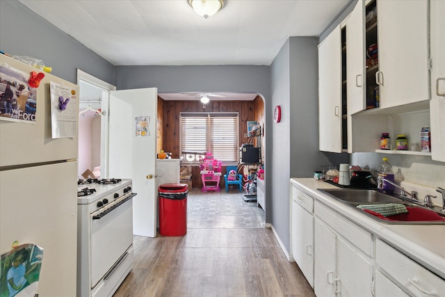 kitchen featuring white appliances, a sink, light countertops, white cabinetry, and arched walkways