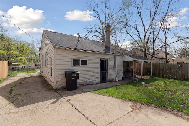rear view of house featuring roof with shingles, a chimney, and a patio