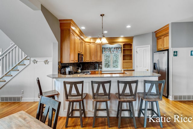 5575 Beechmont Rd, Whitehall, MI 49461 - kitchen featuring light wood-type flooring, light stone countertops, decorative backsplash, a peninsula, and appliances with stainless steel finishes