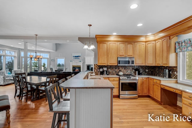 5575 Beechmont Rd, Whitehall, MI 49461 - kitchen featuring a sink, a peninsula, appliances with stainless steel finishes, open floor plan, and a notable chandelier