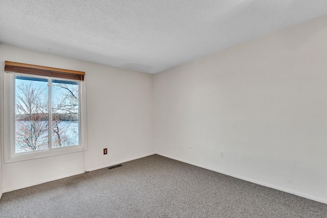 carpeted spare room with a textured ceiling, baseboards, and visible vents