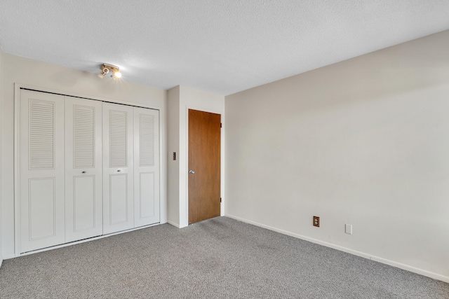 unfurnished bedroom featuring a textured ceiling, a closet, carpet flooring, and baseboards