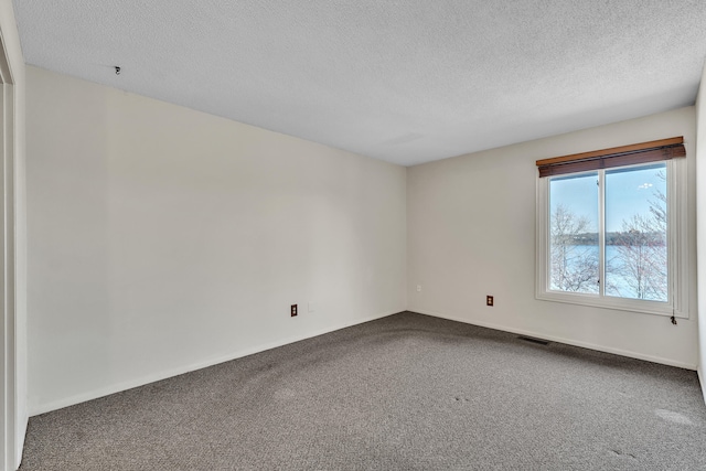 carpeted spare room with baseboards, a textured ceiling, and visible vents