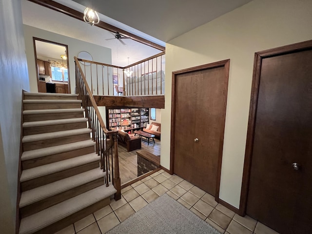 staircase with tile patterned floors, baseboards, and ceiling fan