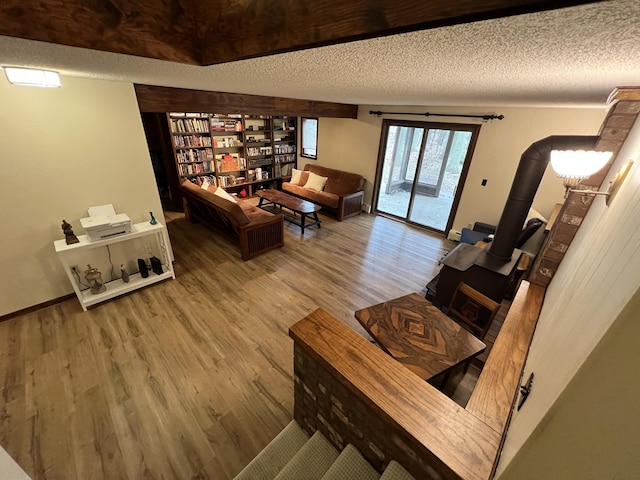 living room with wood finished floors, a textured ceiling, and a wood stove