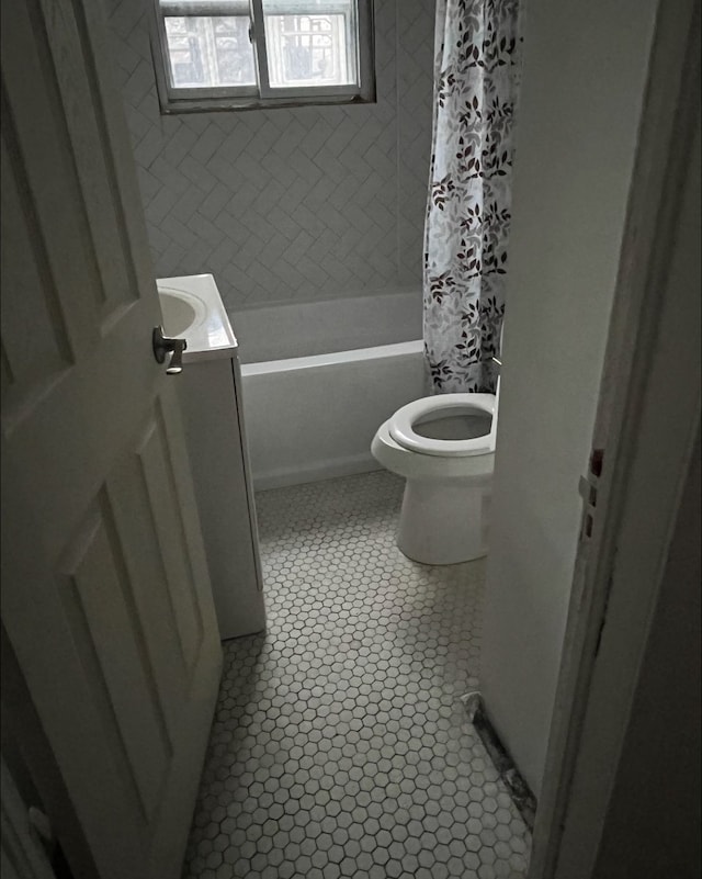 bathroom with vanity, tile patterned flooring, shower / bath combo with shower curtain, and toilet
