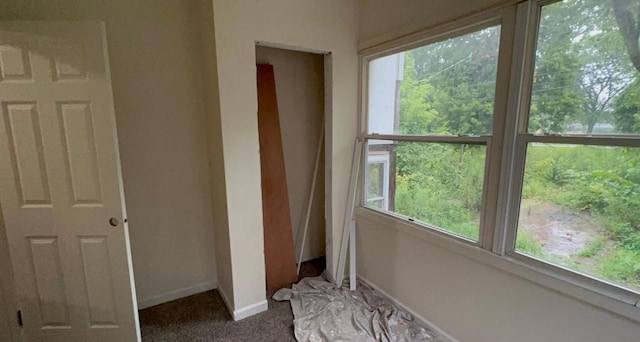 unfurnished bedroom with baseboards, multiple windows, and dark colored carpet