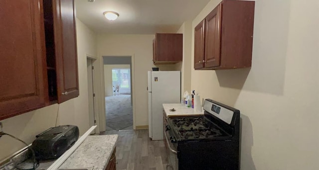 kitchen featuring freestanding refrigerator, light countertops, stainless steel gas range oven, and light wood-type flooring