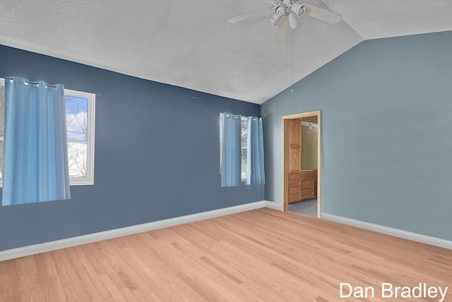 unfurnished bedroom featuring vaulted ceiling, wood finished floors, a ceiling fan, baseboards, and a textured ceiling