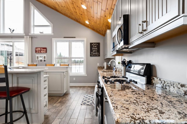 1219 Nokomis Dr, Gladwin, MI 48624 - kitchen with a sink, gas range oven, light wood-style floors, stainless steel microwave, and a breakfast bar area