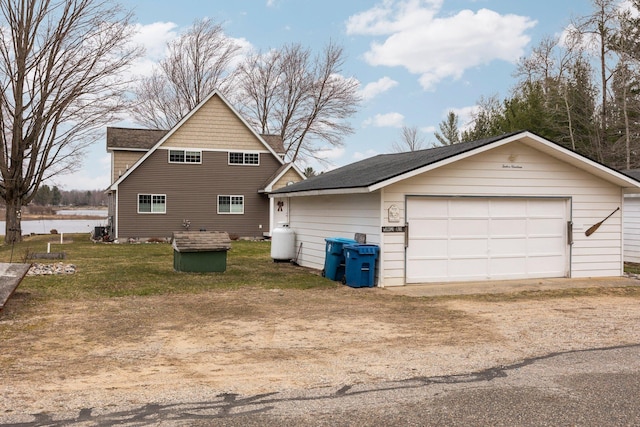 1219 Nokomis Dr, Gladwin, MI 48624 - view of home's exterior with an outdoor structure, a detached garage, driveway, and a water view