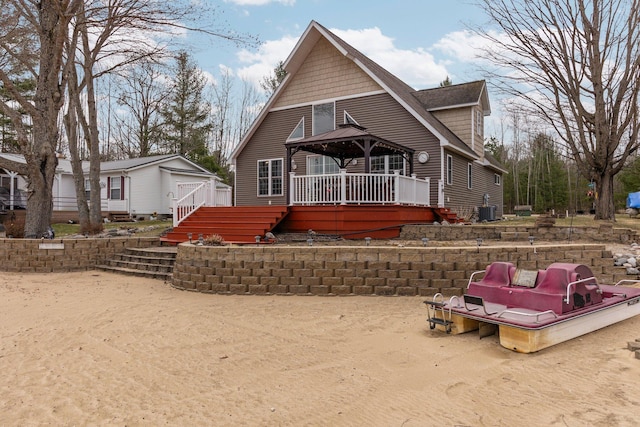 1219 Nokomis Dr, Gladwin, MI 48624 - chalet / cabin with cooling unit, roof with shingles, stairway, and a deck